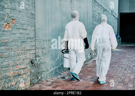 Operatori sanitari che indossano tute protettive contro i noccioli per contribuire a prevenire la diffusione di un'infezione tossica o di una pandemia di covid. I soccorritori puliscono un edificio per una migliore igiene e sicurezza Foto Stock