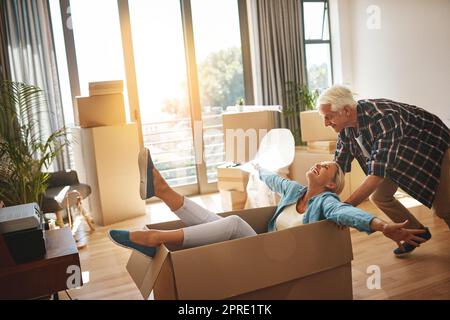 Riempire la loro nuova casa con nuovi ricordi pieni di divertimento. Una coppia matura felice che si diverte nella giornata in movimento. Foto Stock