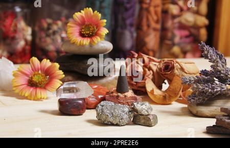 Cono incenso su lastra di pietra con cristalli e fiori Foto Stock