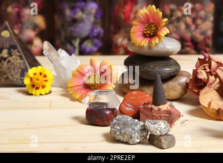 Cono incenso su lastra di pietra con cristalli e fiori Foto Stock