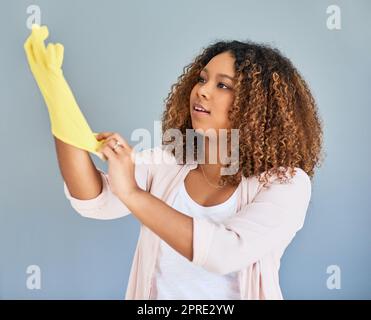 Indossando i guanti, è il momento di lavarsi. Studio shot di una giovane donna attraente indossare guanti di gomma su uno sfondo grigio. Foto Stock