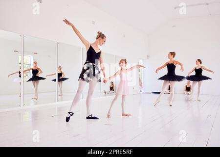 Insegnante di balletto o insegnante che insegna una giovane ballerina in una classe o in uno studio di danza preparandola per uno spettacolo. Giovane bambina che impara ad essere una ballerina e si allena per un allenatore Foto Stock