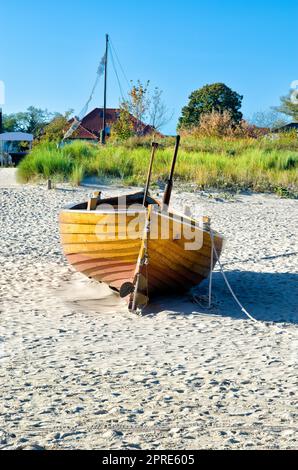 Sulla spiaggia di sabbia si trova una piccola barca da pesca in legno sul mare Foto Stock