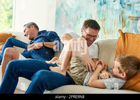 Il suo tempo solletico. Una famiglia affettuosa di quattro persone sul divano di casa. Foto Stock