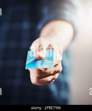 Primo piano su un uomo che acquista o acquista con una carta di credito in mano. Maschio caucasico che riceve bollette da pagare con una carta di debito, pronto a fare shopping. Un ragazzo occasionale che paga una cassiera del negozio per l'acquisto commerciale. Foto Stock