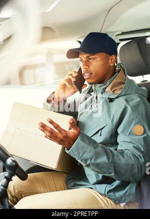 Sono a pochi minuti di distanza con la vostra consegna. Un corriere che parla su un cellulare mentre seduto in un furgone di consegna. Foto Stock