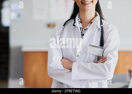 Sicuro e capace. Una donna irriconoscibile medico in piedi con le braccia ripiegate in un ospedale. Foto Stock