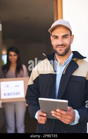 Il nostro servizio di consegna supera di gran lunga tutto. Ritratto di un corriere utilizzando un tablet digitale mentre si effettua una consegna a un cliente. Foto Stock