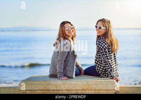 La vista da qui è fantastica. Ritratto di due attraenti giovani donne che trascorrono una giornata in riva al mare. Foto Stock