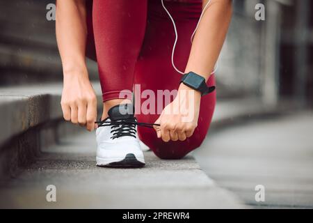 Nessuna estremità allentata. un'atleta femminile irriconoscibile che si lega ai lacci mentre corre all'aperto Foto Stock