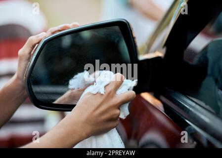Ora possiamo vedere di nuovo nello specchio: Un bambino irriconoscibile che lava l'auto dei genitori fuori durante il giorno. Foto Stock