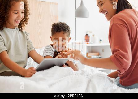 Madre, figlia e figlio su un tablet che si rilassano a casa, guardano divertenti cartoni animati e trascorrono del tempo insieme. Famiglia felice, su un dispositivo digitale che impara e gioca a un gioco nella camera da letto dei bambini. Foto Stock