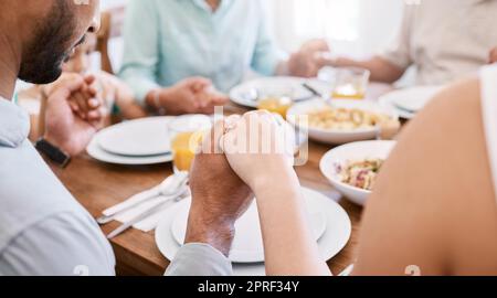 Rimaniamo insieme perché preghiamo insieme. una bella famiglia benedice il cibo con una preghiera al tavolo insieme a casa Foto Stock