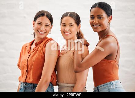 Vaccinazione COVID o influenza sparata all'interno di ragazze amiche, amicizia femminile e adolescenti sorridenti. Ritratto di un gruppo di amici felice e diversificato in piedi e praticare buone abitudini di salute insieme Foto Stock