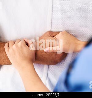 Sei in mani sicure. Primo piano di una mano di persone non riconoscibili che è tenuto da un medico all'interno di una clinica medica. Foto Stock