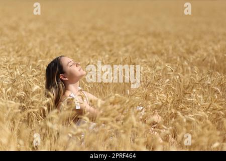 Donna che respira aria fresca in un campo di grano dorato Foto Stock