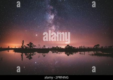 Paesaggio naturale del lago. Night Starry Sky, la via Lattea Galaxy con stelle brillanti e Luna. Riflesso del cielo notturno della natura in acqua. Cielo colorato nei colori blu e viola Foto Stock