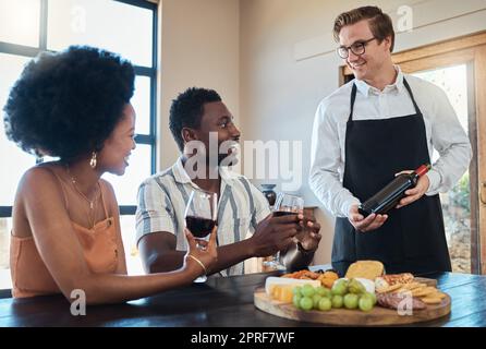 Settore alberghiero, servizio di ristorazione e cameriere che mostra vino a coppia in un appuntamento romantico, parla e sembra felice. Gli amanti si divertono a conversare con il sommelier e a celebrare la loro relazione Foto Stock