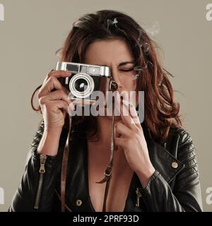 Dove la sua dipendenza e passione si incontrano. Una giovane donna che scatta foto mentre fuma una sigaretta Foto Stock