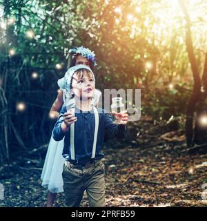 Non ti ferisco, voglio solo giocare. Due piccoli fratelli che catturano lucciole in vasi all'esterno. Foto Stock