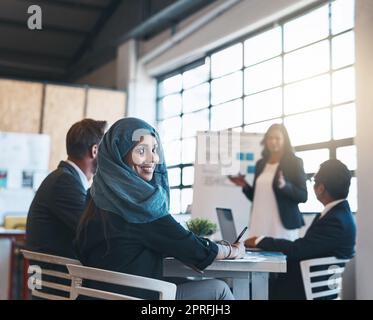 Grandi mosse nella sala riunioni. Ritratto di una donna d'affari araba sorridente che partecipa a una presentazione con i suoi colleghi in ufficio. Foto Stock