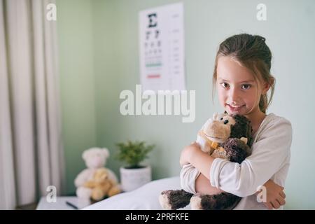 La scimmia è qui per calmarmi. Dottore. Una bambina che tiene la scimmia farcita mentre visita il dottore. Foto Stock