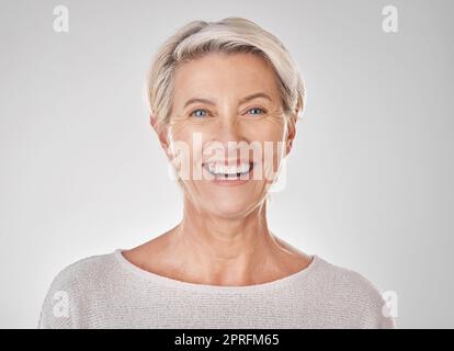 Donna anziana con un sorriso per la salute dentale, bellezza cura della pelle e contenuti faccia contro sfondo mockup studio. Ritratto di modello felice con denti sani, trucco facciale e benessere in pensione Foto Stock