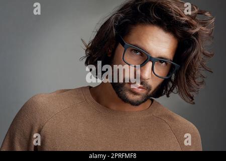 Elegante e geek. Studio di un bel giovane uomo che indossa occhiali su sfondo grigio. Foto Stock
