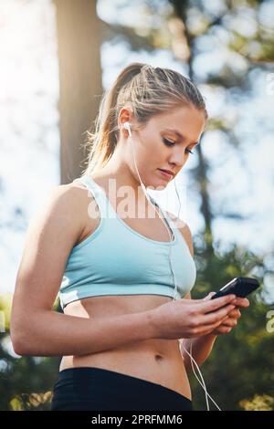 La canzone giusta può cambiare tutto. Una giovane donna che usa il suo telefono all'aperto. Foto Stock