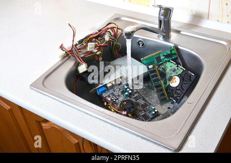 Pulizia del concetto di hardware. Il lavaggio della scheda madre, il disco rigido e l'alimentazione del calcolatore nel lavello. Anche un simbolo per la realizzazione di un grande errore Foto Stock