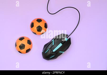 Due palloni da calcio con il mouse del computer su sfondo viola. Concetto di videogiochi, eSports, sport scommesse e gioco d'azzardo online Foto Stock