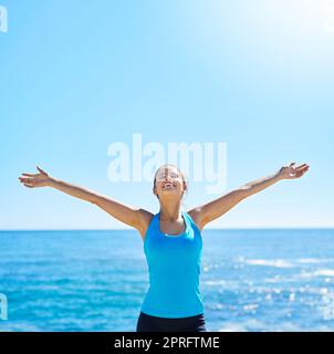 La corsa mi collega con il mio corpo, una giovane donna sportiva in piedi con le braccia distese sulla spiaggia. Foto Stock