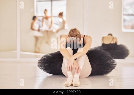 Balletto, depressione e ballerina triste dopo la pratica teatrale, le prove di danza o lo spettacolo in una sala da ballo o in uno studio. Stanco, prepotente e stress di ballerini professionisti seduti a piangere sul pavimento Foto Stock