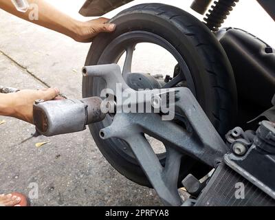 Primo piano di un meccanico di una motocicletta utilizzando una pistola ad aria per allentare i dadi delle ruote in un'officina meccanica Foto Stock