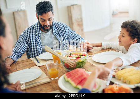 Ringraziate sempre per le vostre benedizioni: Una famiglia che prega insieme prima di gustare un pasto al tavolo. Foto Stock