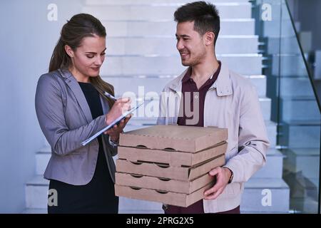 Il pranzo viene consegnato a un uomo che fa una pizza consegnata a una donna d'affari al lavoro. Foto Stock