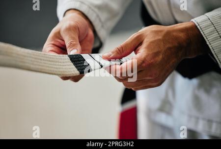 .Fitness, allenamento e mani insegnante di karate preparano l'uniforme per i nuovi studenti in un centro o dojo. Le arti marziali sensei si preparano a condurre una lezione su autodifesa, velocità e resistenza fisica. Foto Stock