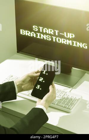 Firma scrittura manuale Avvia brainstorming. Approccio aziendale il team lavora per creare strategie per una nuova donna d'affari che tiene telefono e presenta informazioni importanti sullo schermo Foto Stock