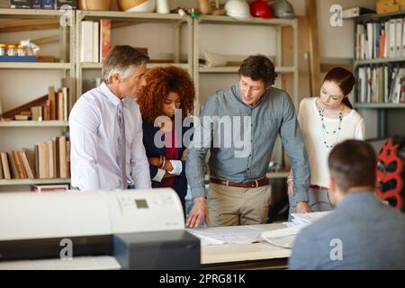 Ispezionando ogni dettaglio del loro progetto edilizio, un gruppo di architetti che lavorano insieme in un ufficio. Foto Stock