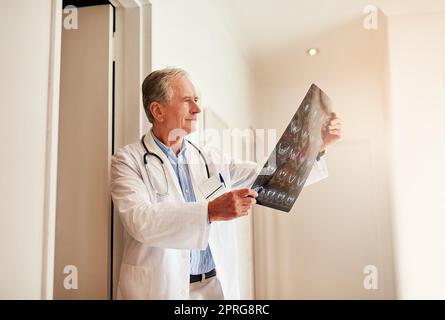 Sì, questo conferma ciò che ho pensato: Un medico maturo che tiene in mano una radiografia per esaminarla. Foto Stock