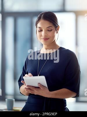 Fare soldi per soddisfare i clienti online. Una donna d'affari che usa il suo tablet in ufficio. Foto Stock