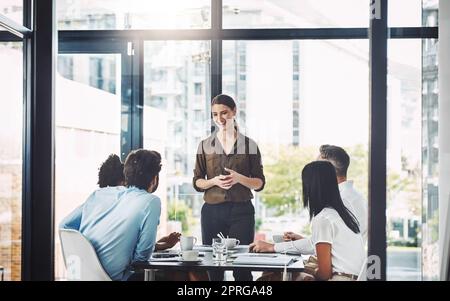 Ci sono alcune opportunità entusiasmanti che ci giungono: Una donna d'affari che presenta i suoi colleghi in una sala riunioni. Foto Stock