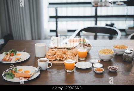 La prima colazione è servita con bevande, caffè, succo d'arancia sul tavolo al mattino a casa Foto Stock