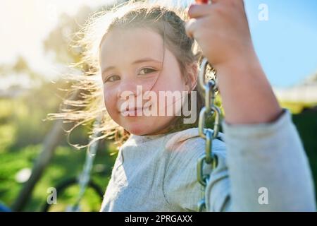 La gioia di essere un bambino. Ritratto di una bambina carina seduta su un'altalena in un parco. Foto Stock