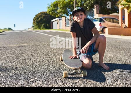 Im un grande skater. Ritratto completo di un ragazzo che gioca con il suo longboard per strada. Foto Stock