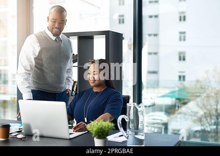 Una seconda opinione: Un giovane uomo d'affari che assiste una collega in ufficio. Foto Stock