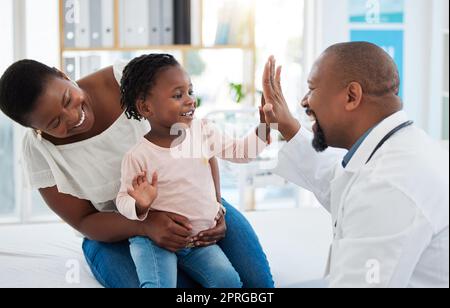 Assistenza sanitaria, madre e ragazza dà medico alto cinque in uno studio medici. Assicurazione medica, sviluppo sano del bambino e consulenza in un ufficio medici. Donna nera, figlia e pediatra sorridenti Foto Stock