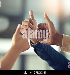 Continuate il lavoro eccezionale. Colpo di primo piano di un gruppo di uomini d'affari che danno i pollici insieme. Foto Stock