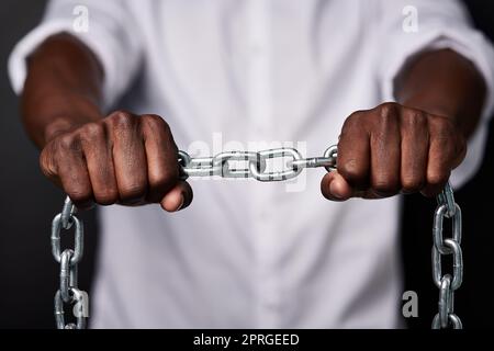 Essere l'anello più forte della catena di vita. Un uomo che tiene una catena di metallo su uno sfondo nero. Foto Stock