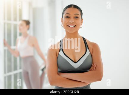 L'elaborazione fuori amplifica la mia fiducia. una giovane donna in forma sorridente mentre si alza con le braccia incrociate Foto Stock